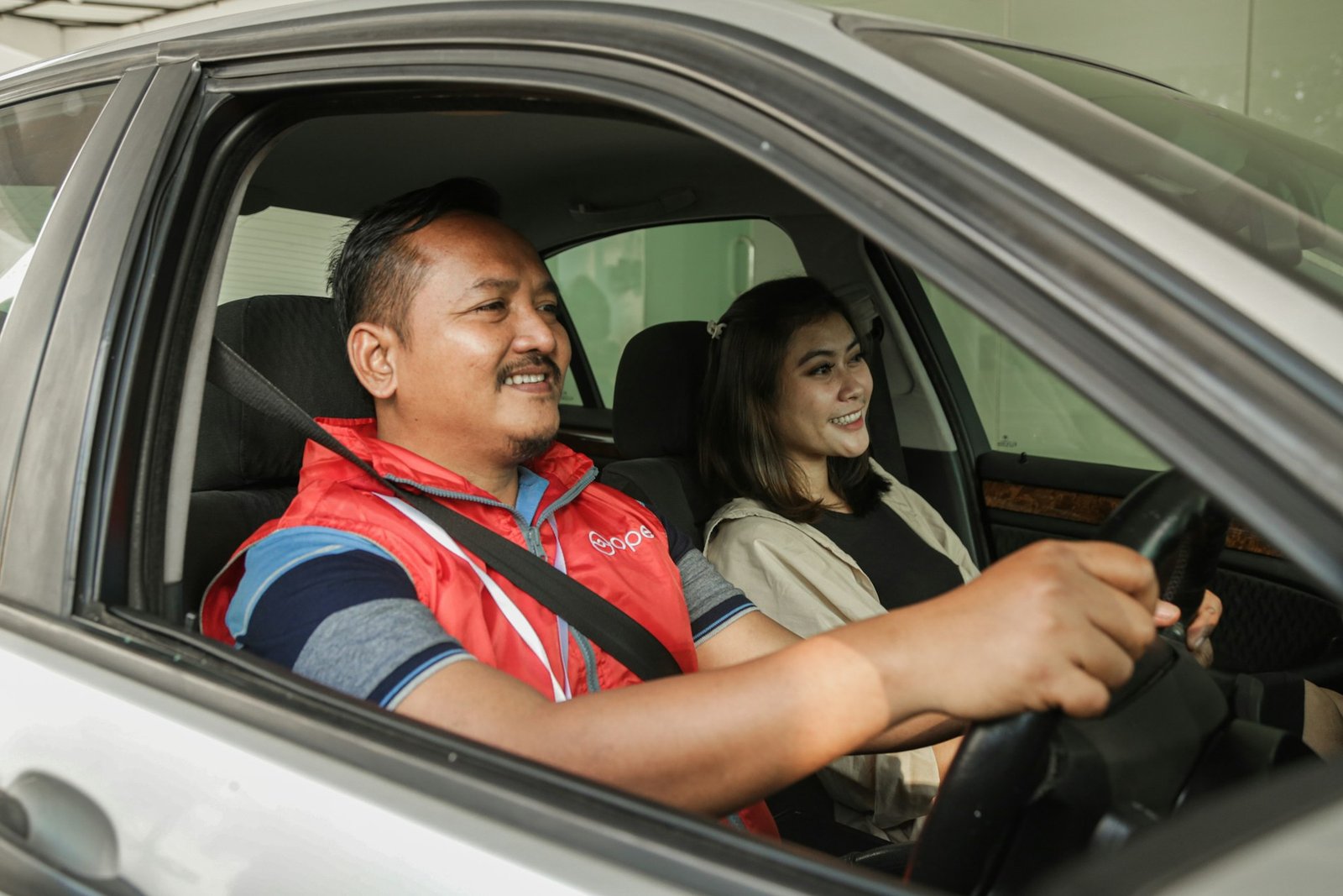Conductor y acompañante sonrientes en los asientos delanteros de un coche
