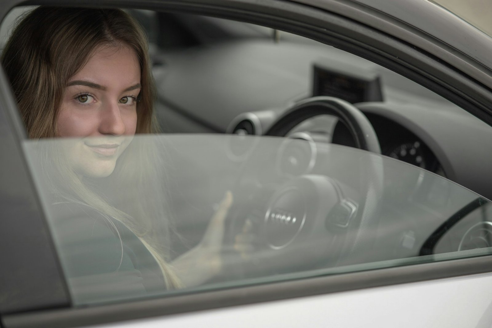 Joven sonriente sentada al volante de un coche