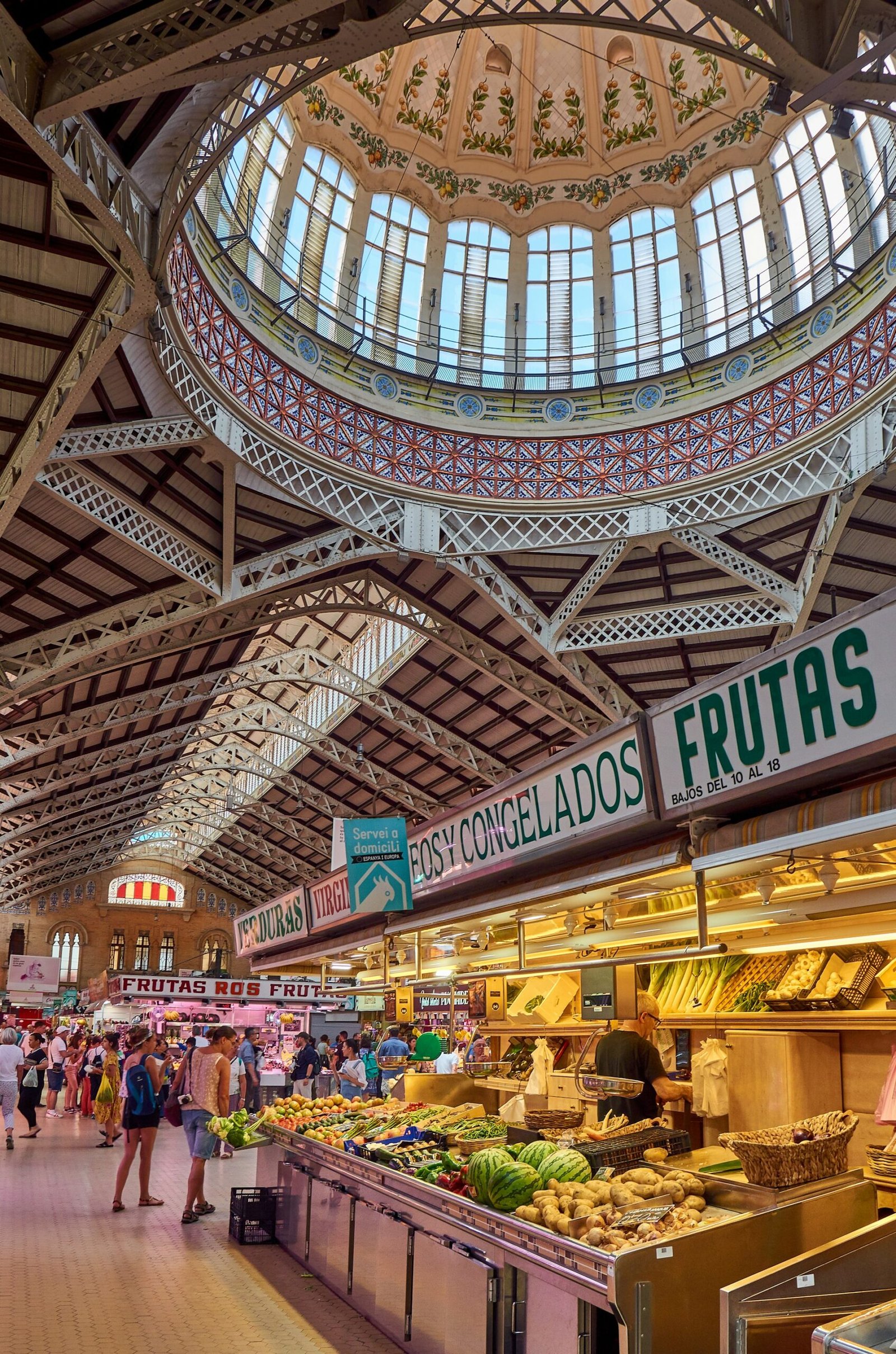 Puestos de fruta y verdura bajo la cubierta de un mercado de abastos