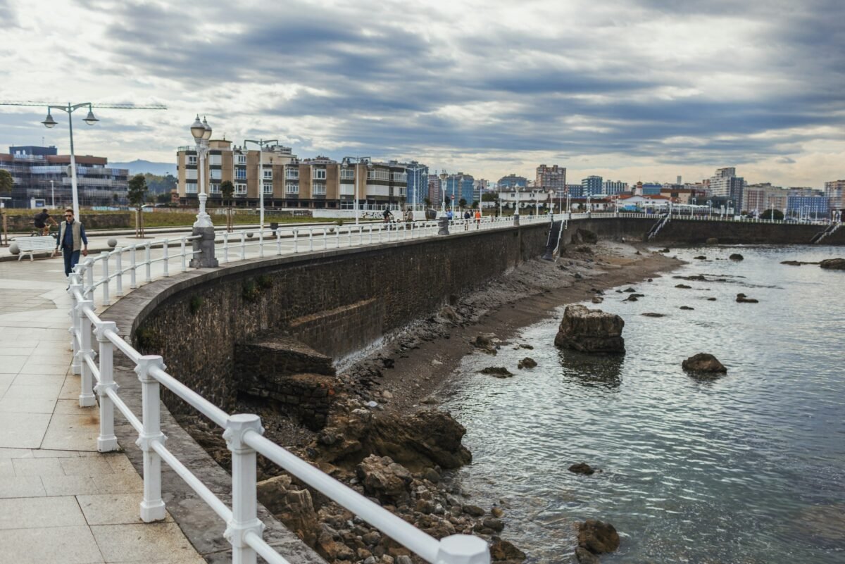 Paseo marítimo de Gijón junto al mar con la ciudad al fondo